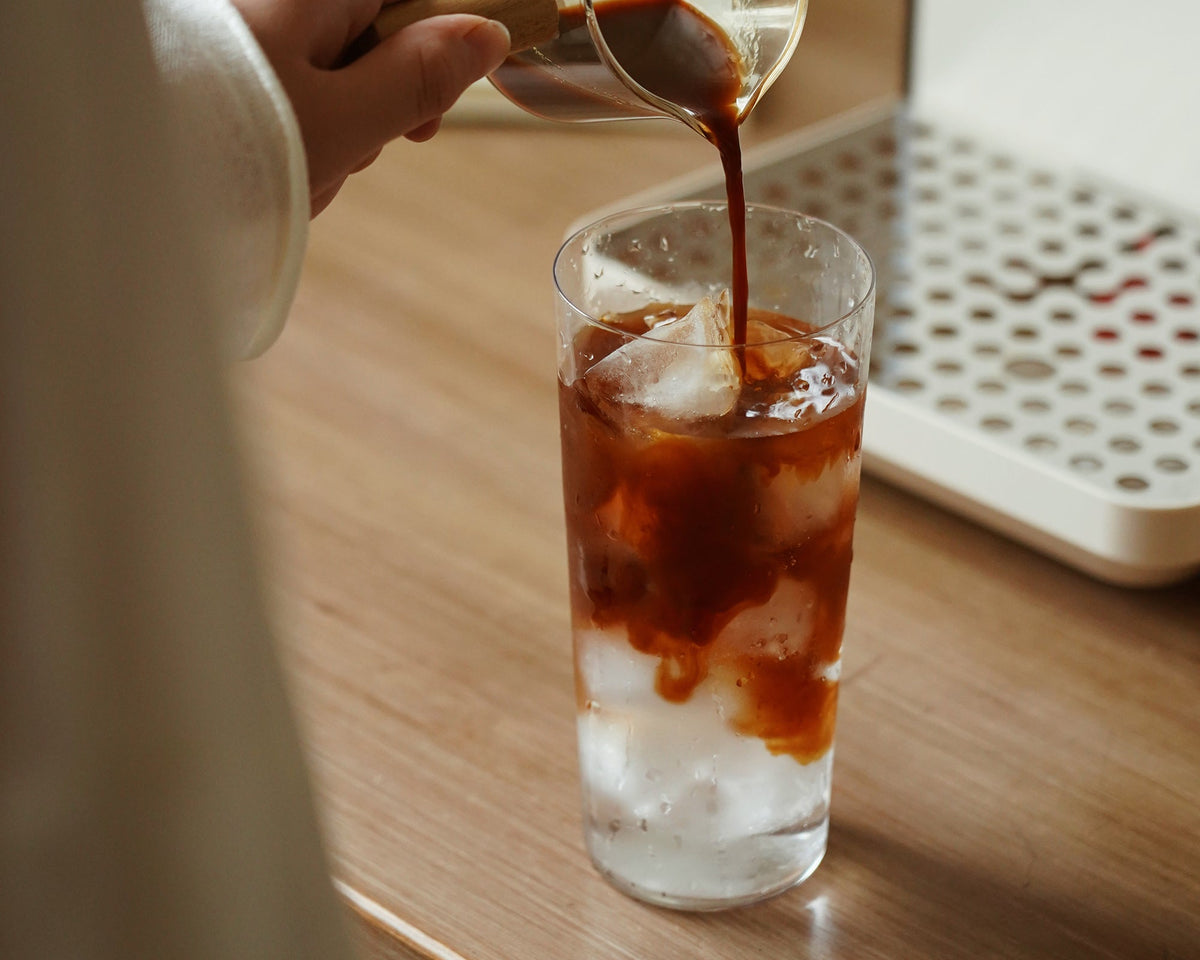 Cold coffee poured into iced milk beside a Gemilai Owl G3006A espresso machine